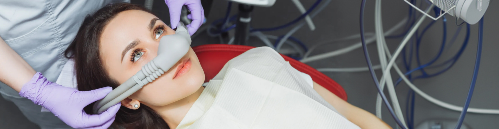 Gloved hands placing breathing mask over woman's nose.